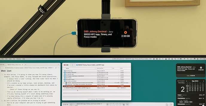 A picture of an iPhone on a microphone mount 'floating' above my monitor. On it is a timer, that tells me I should be working on activity '90033 NFC tags, Timery, and Focus modes' -- which is the video I'm talking about in this post.